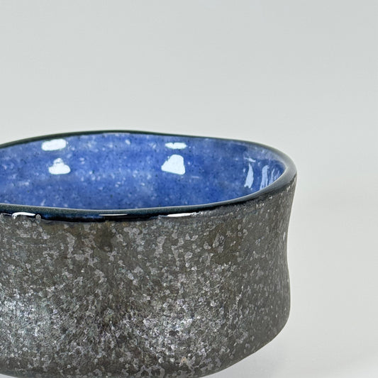 Side detail of Midnight Wave Japanese chawan with speckled charcoal glaze and blue interior rim