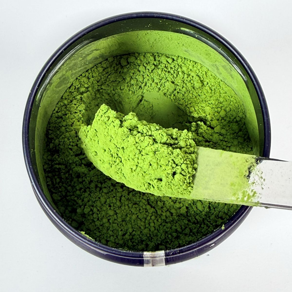 Green powder in a container with a spoon