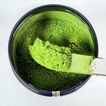 Green powder in a container with a spoon