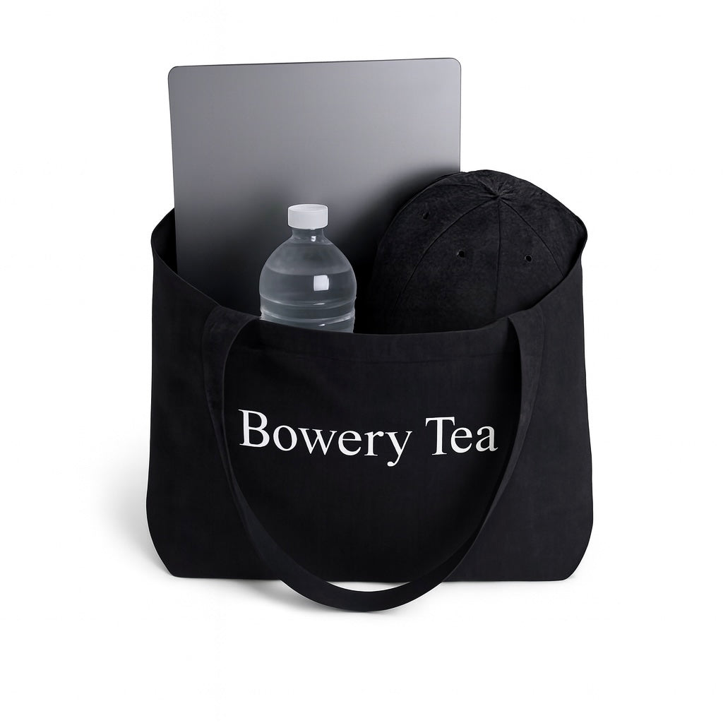 Bowery Tea black canvas tote bag holding laptop water bottle and daily essentials