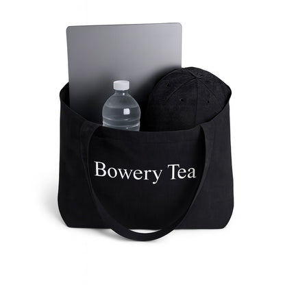 Bowery Tea black canvas tote bag holding laptop water bottle and daily essentials