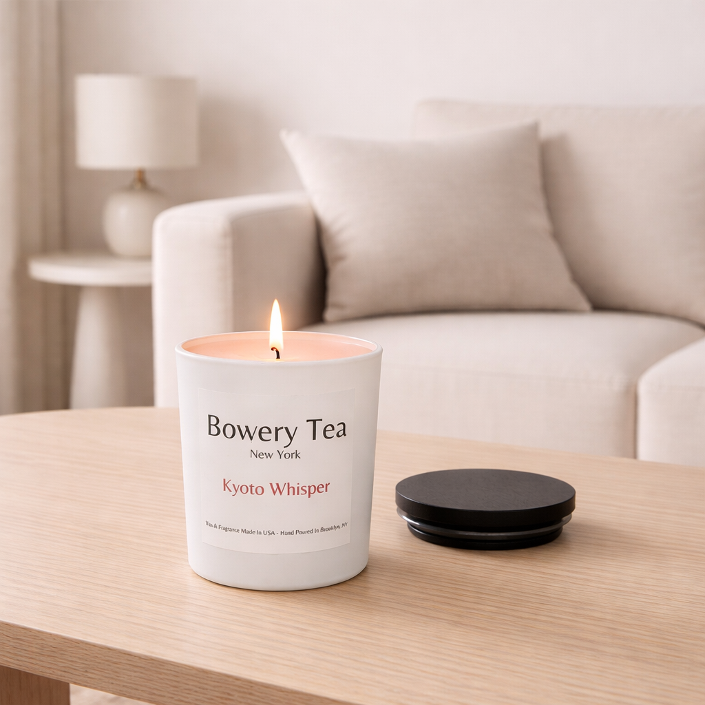 Bowery Tea Kyoto Whisper scented candle lit in white glass jar with wooden lid beside it