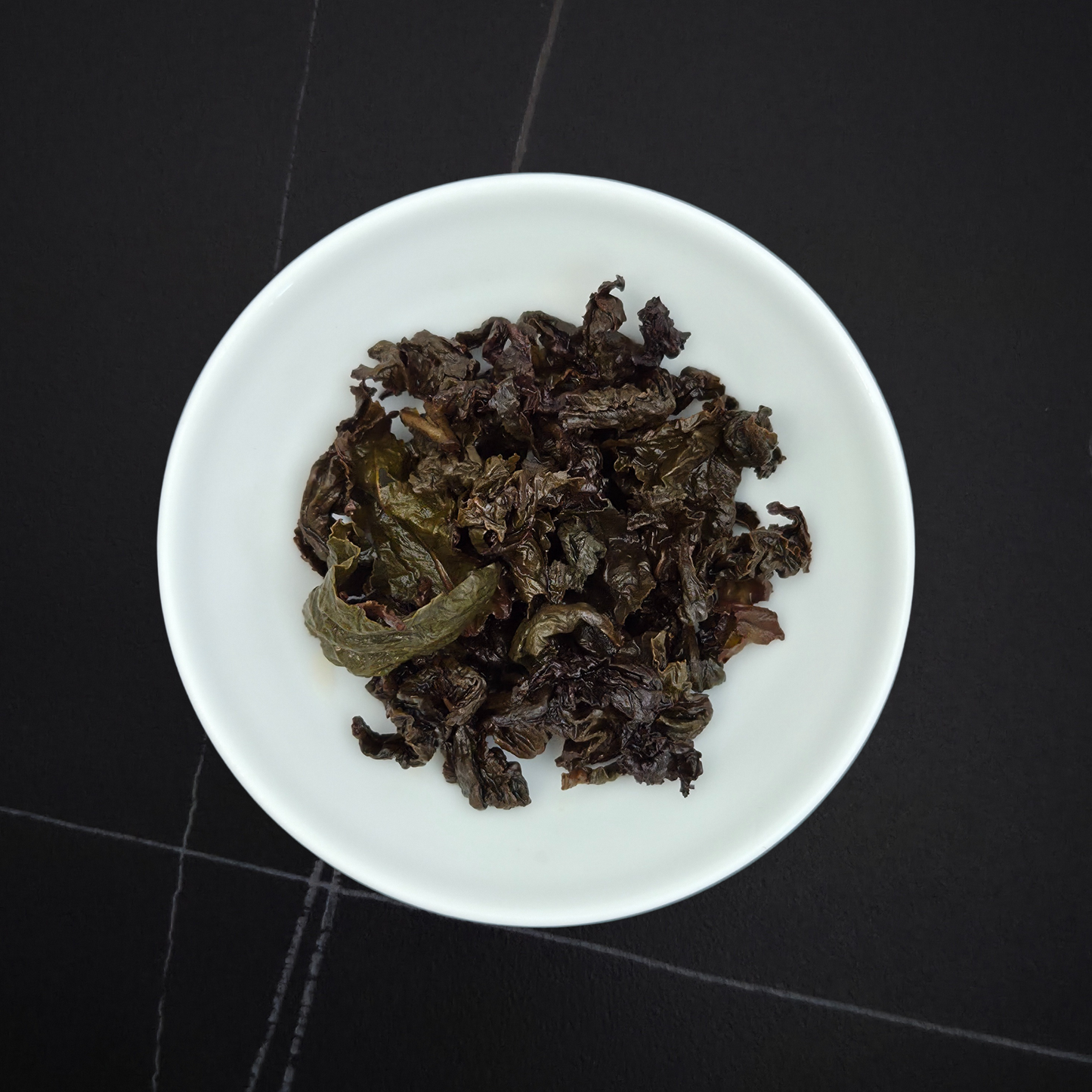 wet leaves of charcoal roasted oolong showing rolled dark leaves