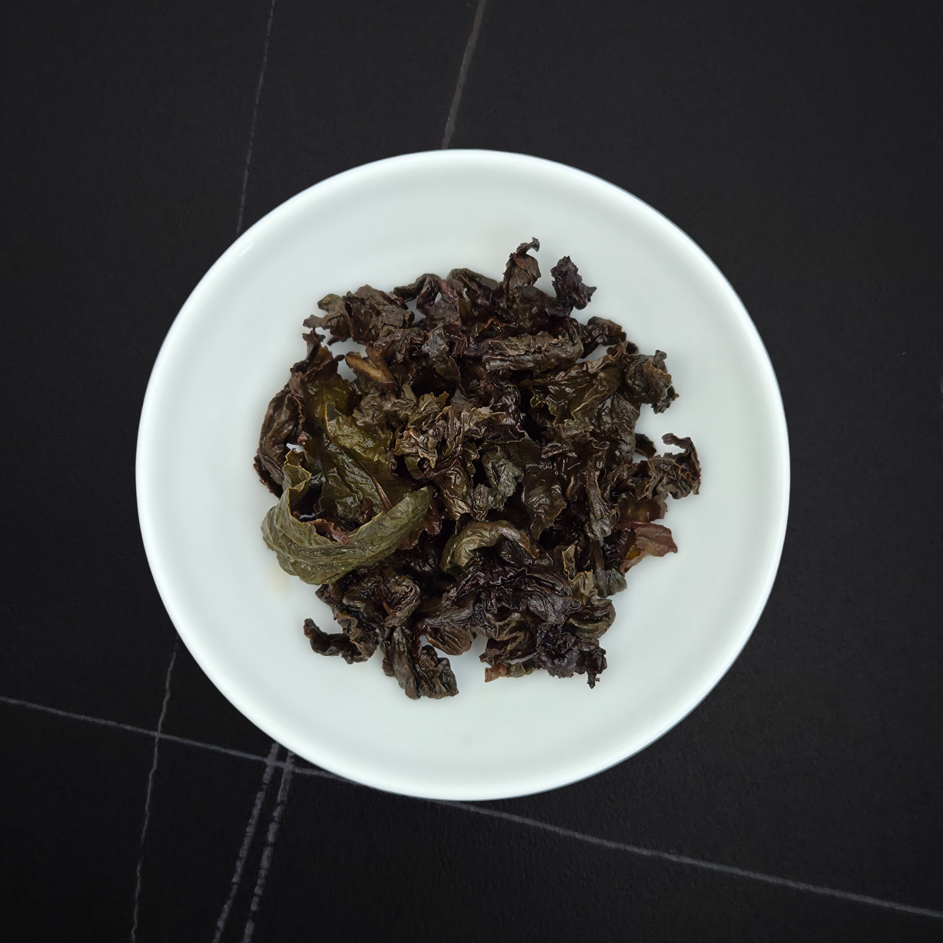 wet leaves of charcoal roasted oolong showing rolled dark leaves