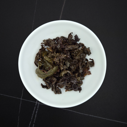 wet leaves of charcoal roasted oolong showing rolled dark leaves