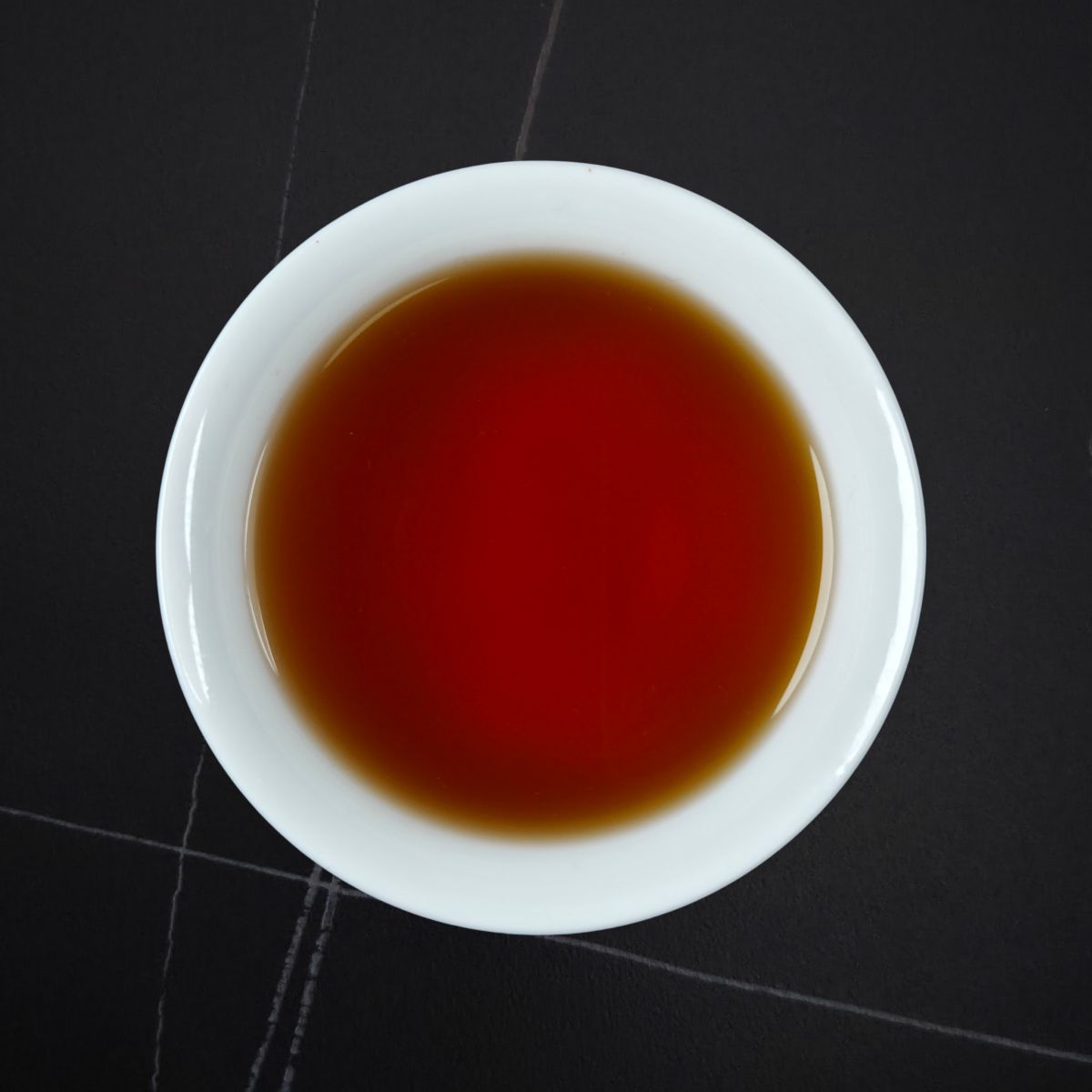 Golden Honey black tea brewed — deep amber-red liquor in a white cup