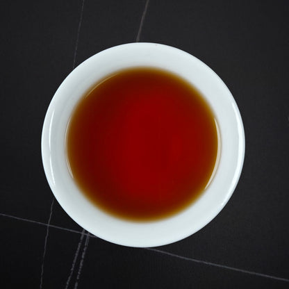 Golden Honey black tea brewed — deep amber-red liquor in a white cup