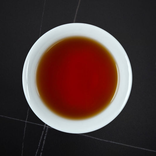 Golden Honey black tea brewed — deep amber-red liquor in a white cup