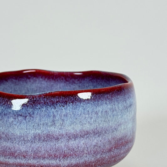 Detail of Crimson Dawn matcha bowl showing red rim and soft lavender blue glaze