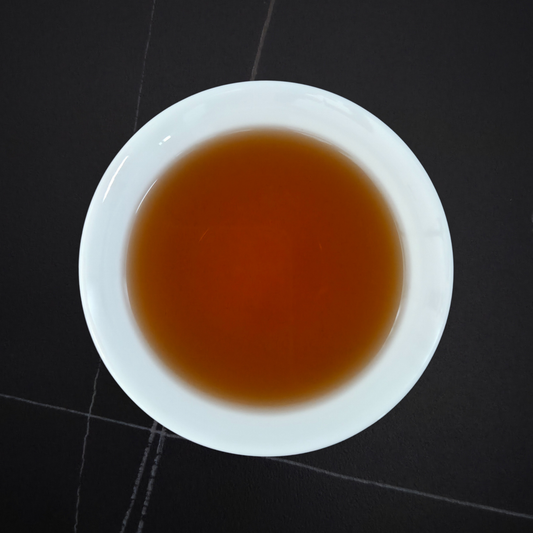 amber liquor of dark roast hojicha in white cup