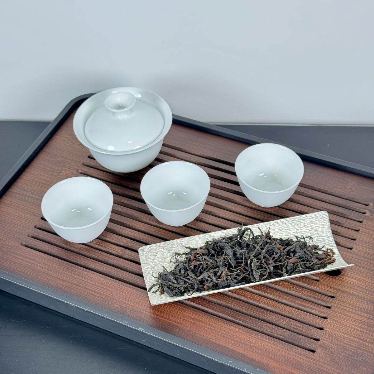 Traditional gongfu tea set with small cups and loose leaf tea on a wooden tray