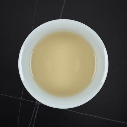 White bowl with beige liquid on a black tiled floor