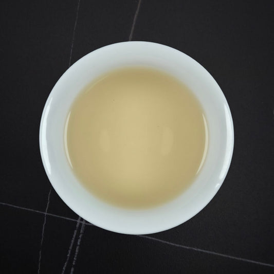 White bowl with beige liquid on a black tiled floor