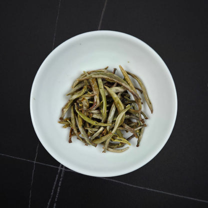 Wet Imperial Silver Needle white tea leaves after brewing in a white tasting cup