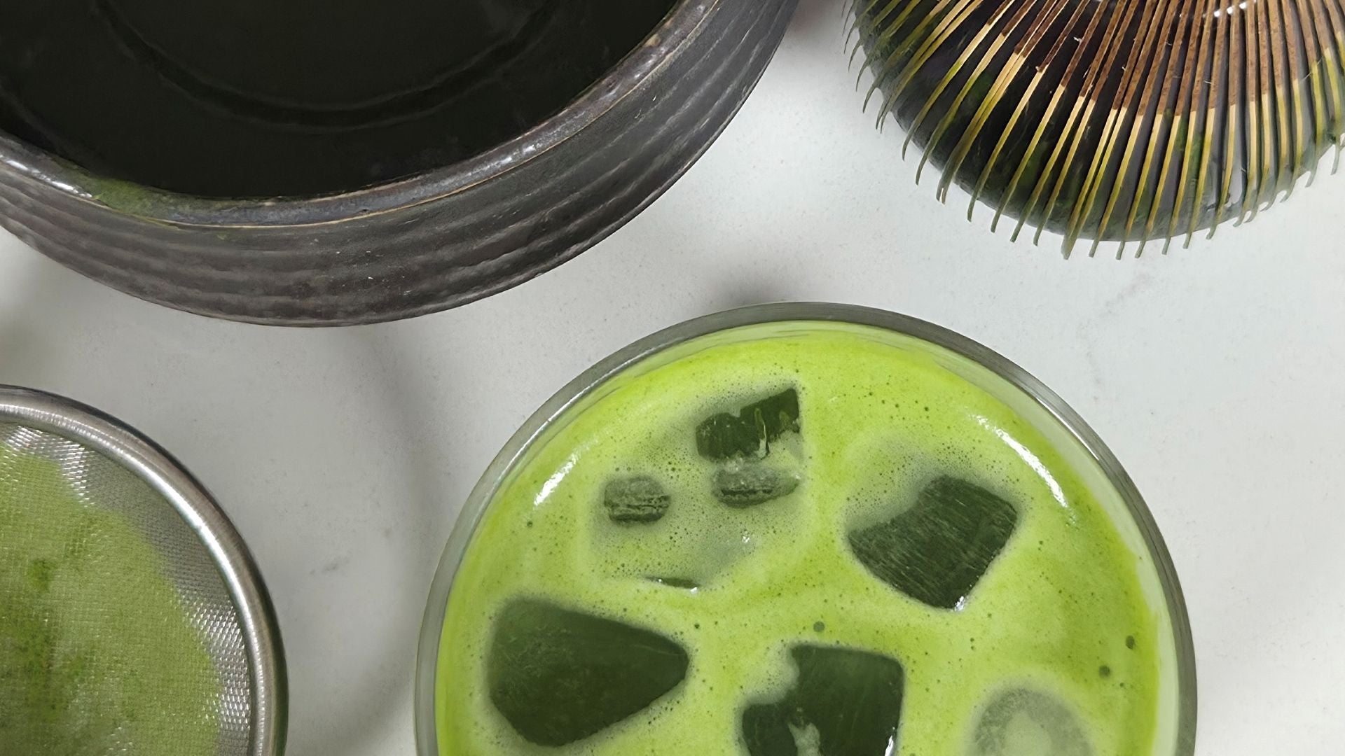 Bowl of iced matcha with foam and ice cubes, representing tea recipes and preparation ideas