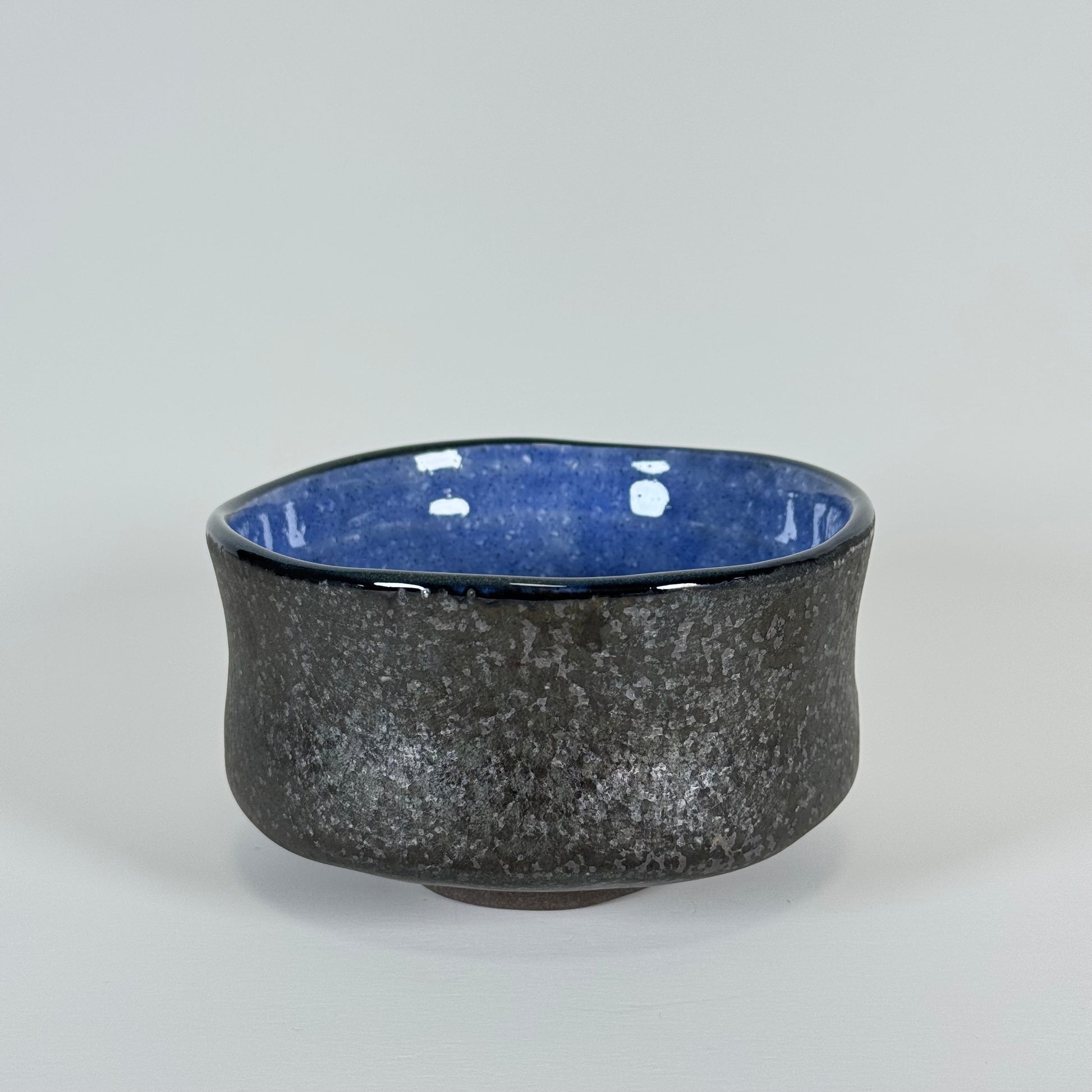 Handmade Japanese matcha bowl with charcoal textured exterior and cobalt blue interior glaze