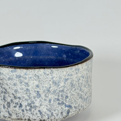 Side detail of handmade Stone Sky matcha bowl with stone-textured ceramic exterior and blue glazed rim