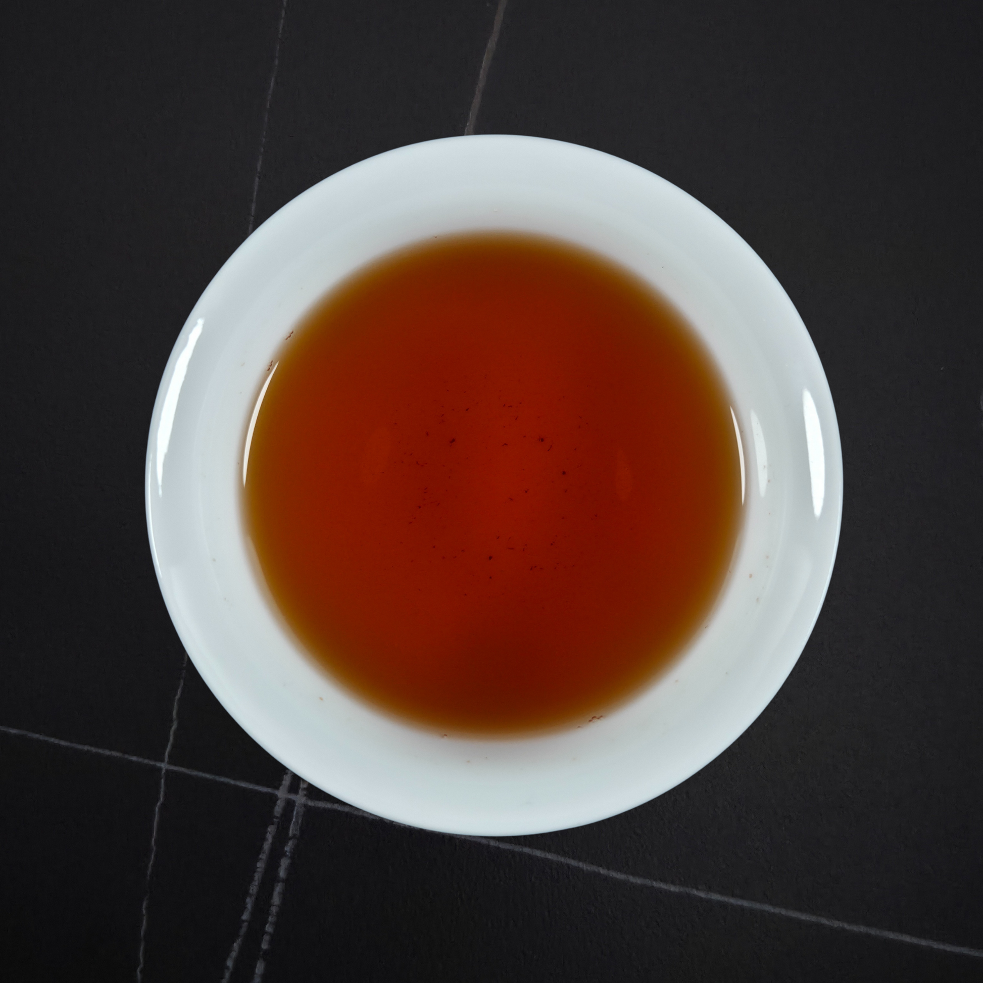Cup of Zheng Shan Xiao Zhong black tea with amber liquor smooth sweet and lightly roasted